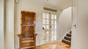 Una silla de madera, una puerta blanca con paneles de vidrio y una escalera.