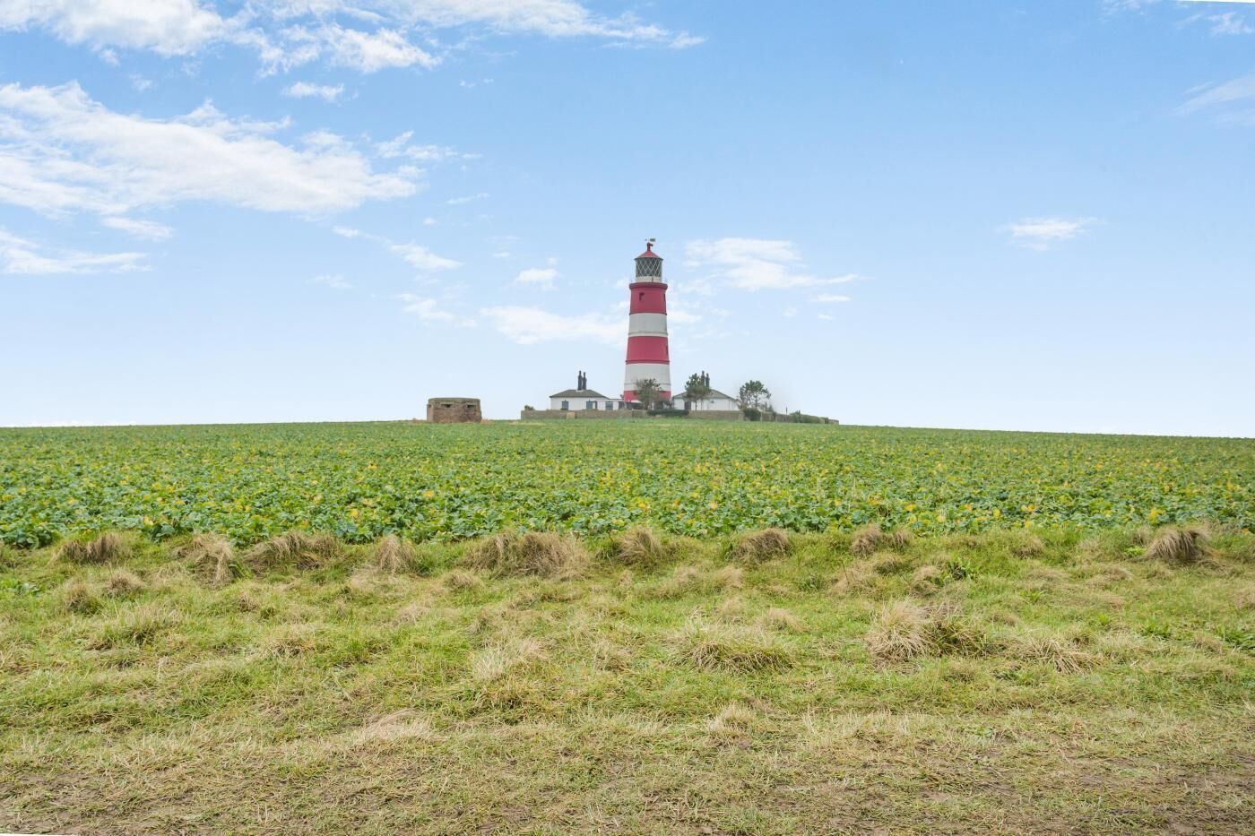 Un phare sur une colline herbeuse, sous un ciel dégagé.