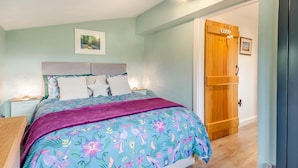 Ein Schlafzimmer mit einem Bett, Nachttischen, einer Holztür und einer Deckenleuchte.