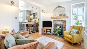 Ein modernes Wohnzimmer mit Kamin, Fernseher und einem gelben Sessel.
