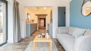 Ein modernes Wohnzimmer mit Sofa, Couchtisch und Blick in eine Küche und einen Flur.