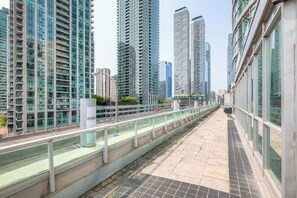 Un moderno paseo urbano flanqueado por edificios de gran altura, con barandillas de vidrio y un camino empedrado.