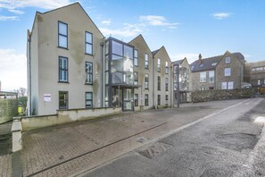 En række moderne bygninger med en central glasindgang, en belagt indkørsel og en stenvæg.