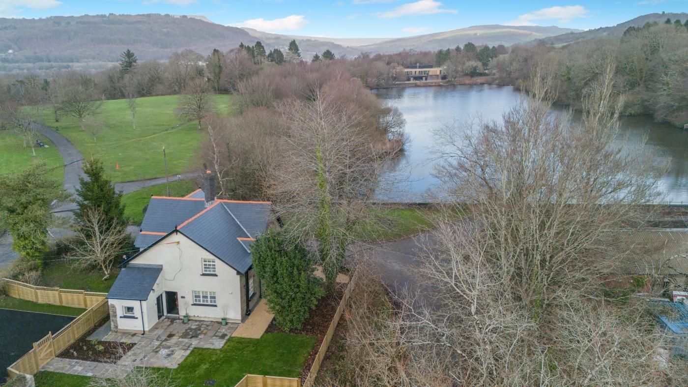 A house with a sloped roof, a fenced yard, and a view of a lake.
