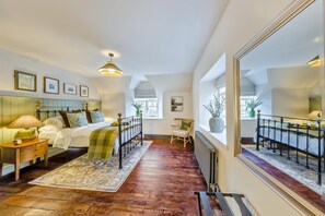 Quarto com cama grande, mesas de cabeceira, espelho e vista do exterior pela janela.