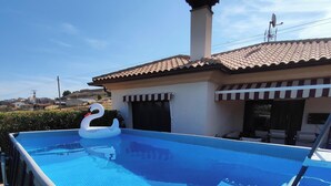 A swimming pool with a swan decoration, a covered patio area, and a building with a tiled roof.