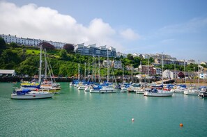 A marina with multiple boats docked, a waterfront view, and buildings in the background. - 7 Bed in Ilfracombe (oc-f34374) (Ilfracombe)