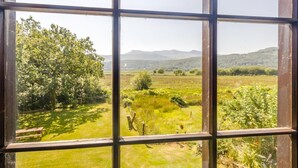 Una ventana con vista a un paisaje verde, que incluye árboles y colinas distantes.