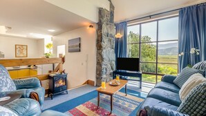 Una sala de estar acogedora con pared de piedra, chimenea, sofá y televisor.