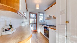 Une cuisine avec des meubles de rangement en bois, un four encastré, un évier et une fenêtre.
