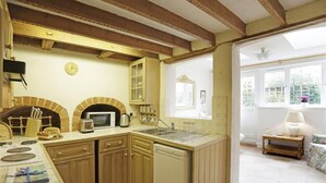 Een keuken met houten kastjes, een magnetron en een bakoven.