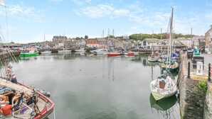A harbor with various boats docked, a clear sky, and buildings in the background. - 2 Bed in Padstow (oc-p00557) (Padstow)