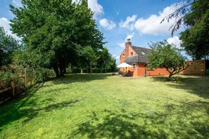 A house with a red exterior, a fenced yard, and a large tree in the foreground. - 2 Bed in Wickhampton (oc-t34449) (Wickhampton)