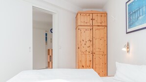 Un dormitorio con una cama, un armario de madera y un cuadro en la pared.