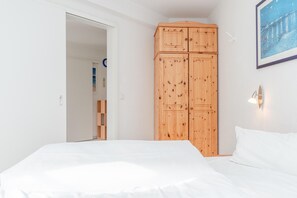 Ein Schlafzimmer mit einem Bett, einem Holzschrank und einem gerahmten Bild an der Wand.