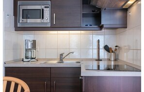 A modern kitchen with a microwave, coffee maker, sink, and cabinets. - Ostseeurlaub in der Ferienwohnung Seepark Sellin auf Rugen (Sellin)
