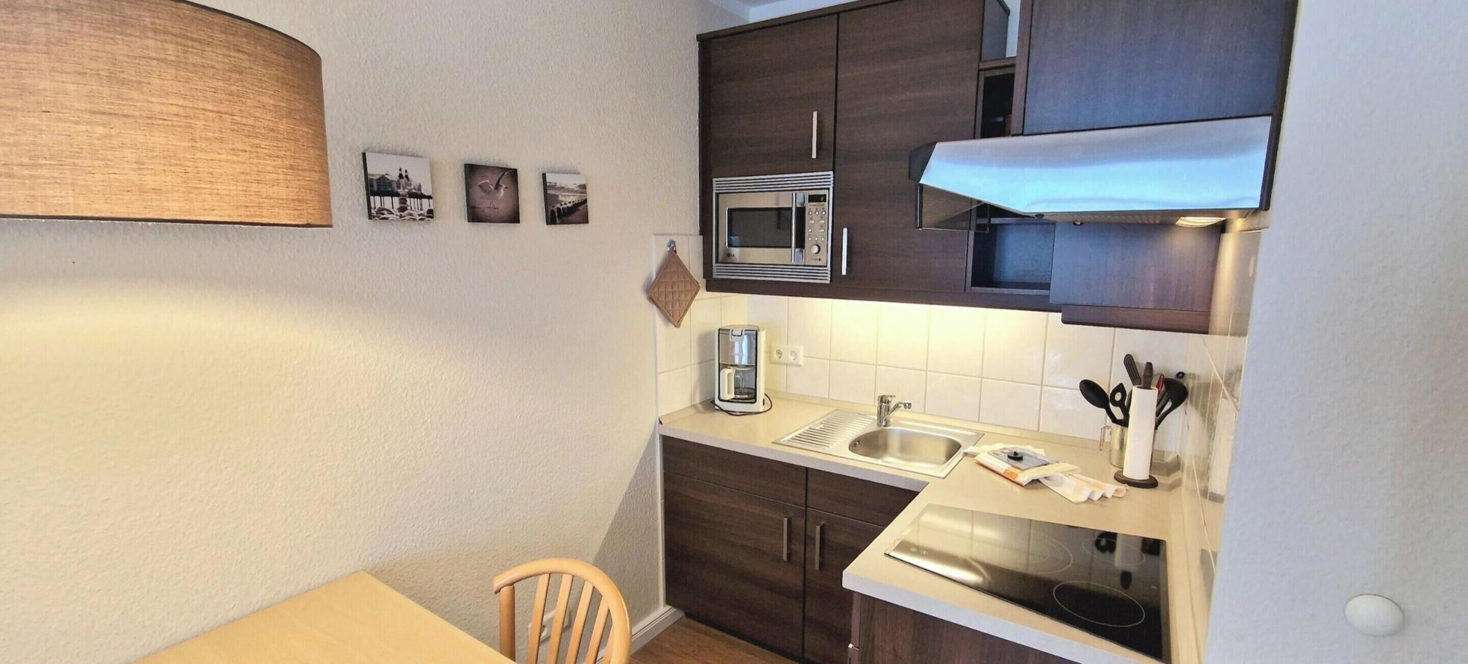Una cucina compatta con forno a microonde, lavello e un piccolo angolo ristoro.
