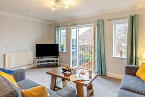 A living room with a flat-screen TV, a wooden coffee table, and a sofa. - 4 Bed in Weymouth (oc-p33952) (Weymouth)