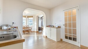 Ett modernt kök med matplats, trägolv och ett stort fönster.
