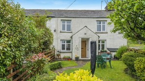 A white house with a wooden door, a garden with a wooden fence, and a table with chairs. - 2 Bed in Ings (oc-s34594) (Ings)
