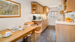 A kitchen with wooden cabinets, a dining table with tea set, and a fruit bowl. - 2 Bed in Ings (oc-s34594) (Ings)