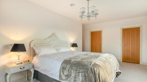 A bedroom with a bed, two bedside lamps, a chandelier, and two wooden doors. - 2 Bed in Duddlestone (oc-q34588) (Duddlestone)