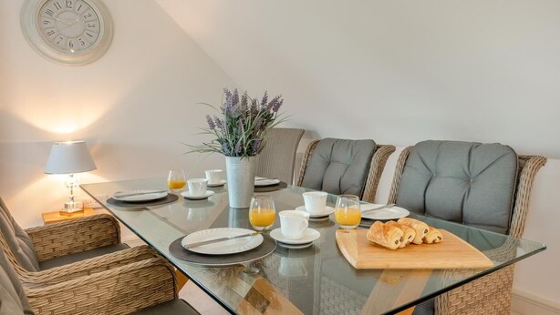 A dining area with a glass table, white plates, glasses, and a plant. - 2 Bed in Duddlestone (oc-q34588) (Duddlestone)