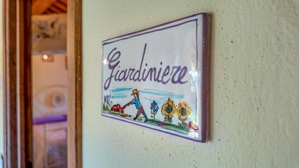 A wall-mounted sign with the word 'Giardinieri' and a drawing of a person tending to flowers.