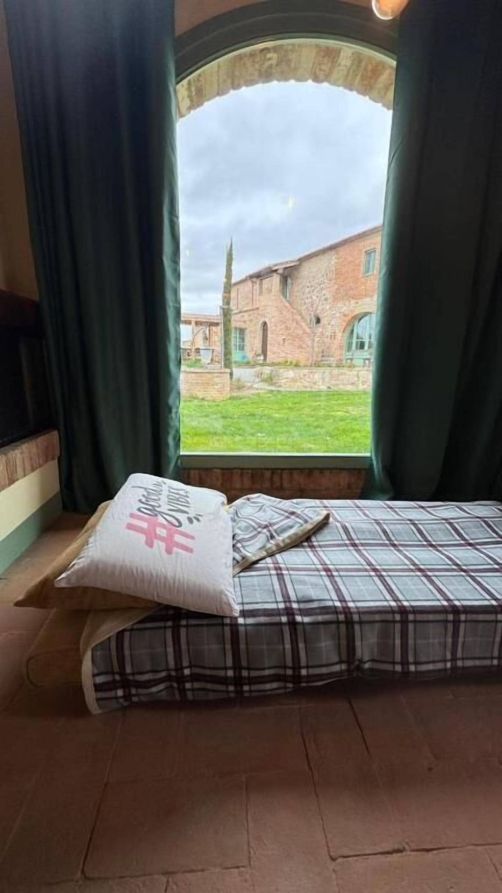 Una habitación con una cama, una ventana con cortinas y vistas a un edificio.