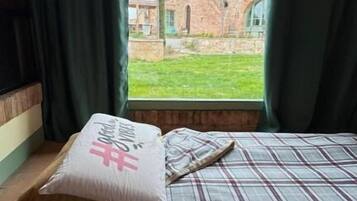 Una habitación con una cama, una ventana con cortinas y vistas a un edificio.
