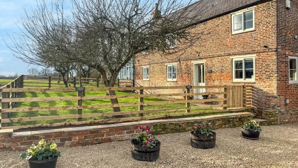 A brick house with a wooden fence, a tree, and gravel paths. - 3 Bed in Cundall (oc-l34088) (Cundall)