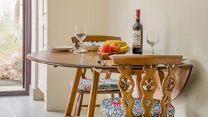 A dining table with a bottle of wine, glasses, and fruit. - 1 Bed in Porthcawl (oc-94806) (Porthcawl)