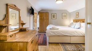 A bedroom with a bed, a wooden dresser, a television, and a wardrobe. - 1 Bed in Porthcawl (oc-94806) (Porthcawl)