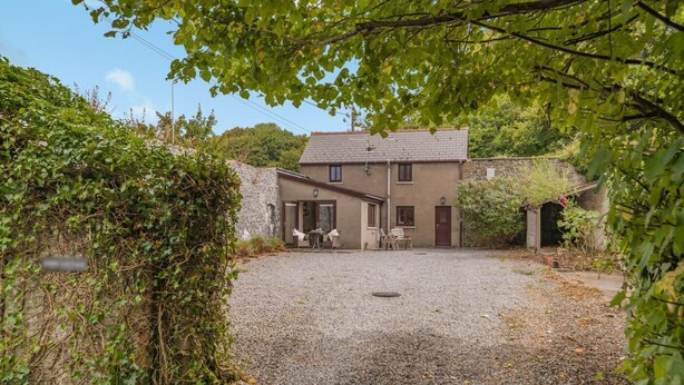 A two-story house with a gravel driveway, a patio with outdoor furniture, and a garden area. - 1 Bed in Porthcawl (oc-94806) (Porthcawl)