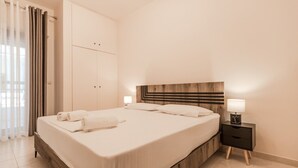 A modern hotel room with a large bed, a wooden headboard, a bedside table with a lamp, and a wardrobe. - Lora House by RentalsPro - Nea Moudania (Nea Moudania)
