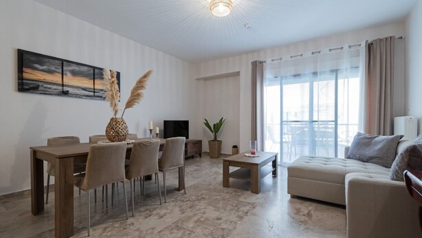 A modern living room with a dining area, a sofa, and a TV. - Lora House by RentalsPro - Nea Moudania (Nea Moudania)