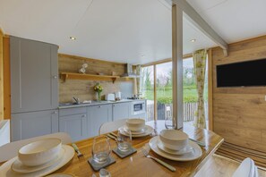 A modern kitchen with grey cabinets, a wooden countertop, and a dining area set for four with plates, bowls, and cutlery.