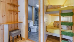Ein kleines Zimmer mit einem Etagenbett, einer kleinen Bank und einer Toilette.