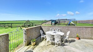 A patio with outdoor furniture, a view of a playground, and a rural landscape. - 3 Bed in Abersoch (oc-25959) (Llangian)