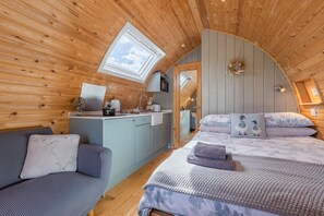 A cozy cabin with a loft bedroom, a kitchenette, and a seating area.