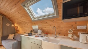 Eine gemütliche Küche mit Oberlicht, Holzboden und einem modernen Waschbecken.