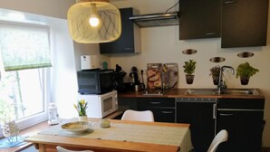 Cozinha moderna com mesa de jantar, cadeiras, luminária pendente e janela com vista.