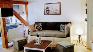 Uma sala de estar com um sofá, uma mesa de centro, um abajur e um quadro na parede.