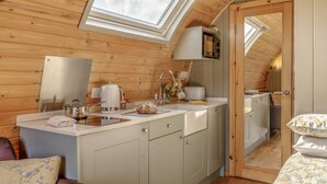 Eine kleine Küche mit Dachfenster, Spüle und Mikrowelle.