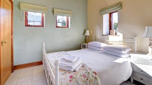 Ein Schlafzimmer mit einem Bett, zwei Nachttischen, einem Schranken und einem Fenster mit Blick.