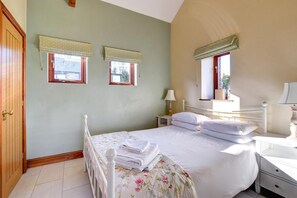 Ein Schlafzimmer mit einem Bett, zwei Nachttischen, einem Schranken und einem Fenster mit Blick.