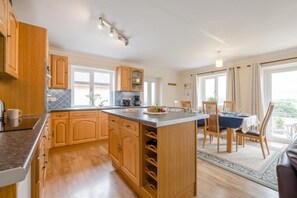 Una cocina amplia con armarios de madera, una isla central y una zona de comedor con mesa y sillas.