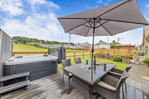A deck with a hot tub, outdoor table, chairs, and a large umbrella. - 2 Bed in Bala (oc-82212) (Bala)
