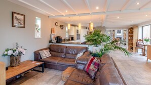 Ein geräumiges Wohnzimmer mit einer Ledersofa, einem Couchtisch und einem Essbereich mit Holztisch und Stühlen.