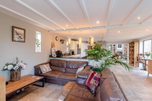Ein geräumiges Wohnzimmer mit einer Ledersofa, einem Couchtisch und einem Essbereich mit Holztisch und Stühlen.